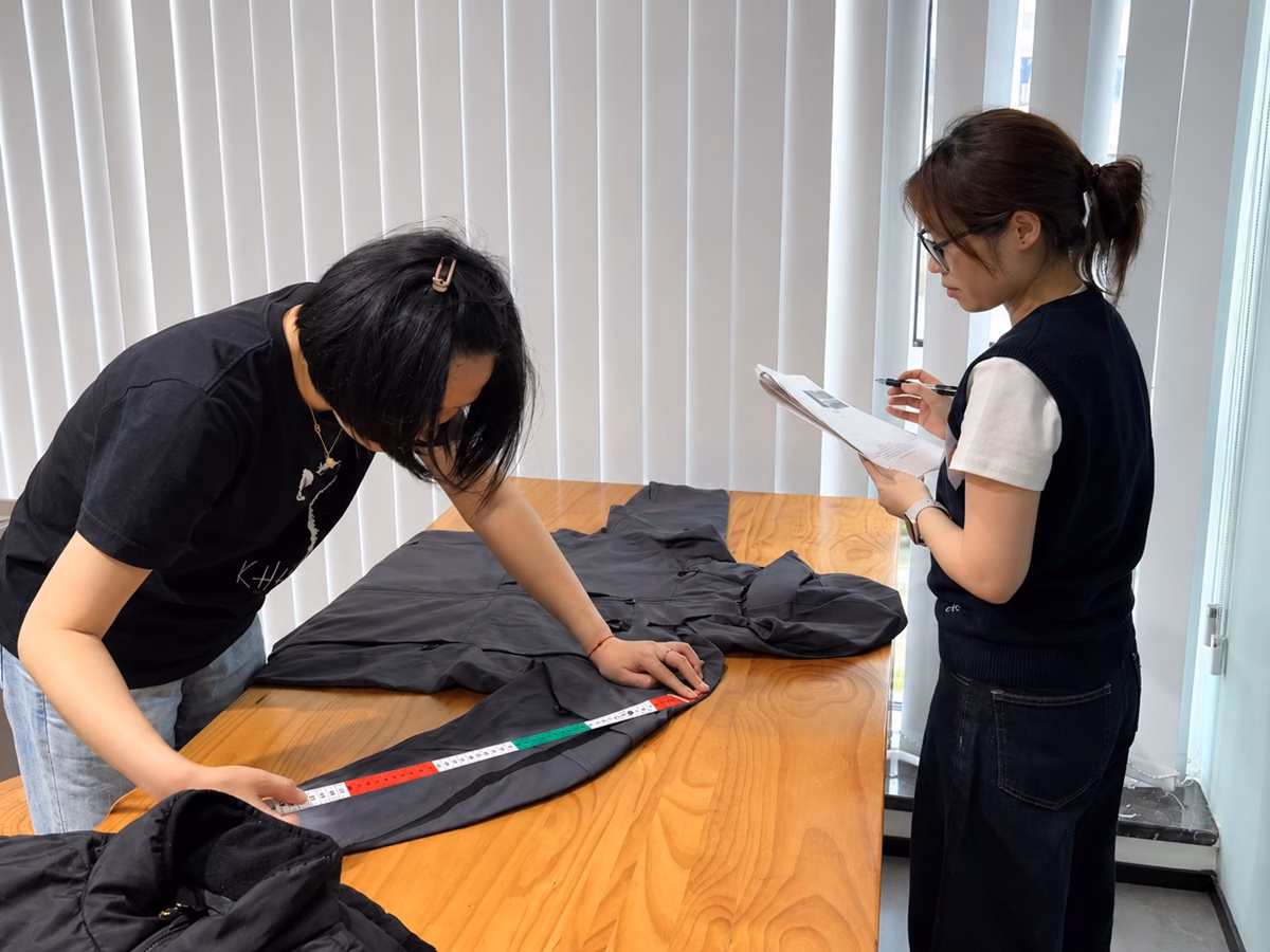 Varytex team measuring a functional garment and reviewing specifications during quality inspection