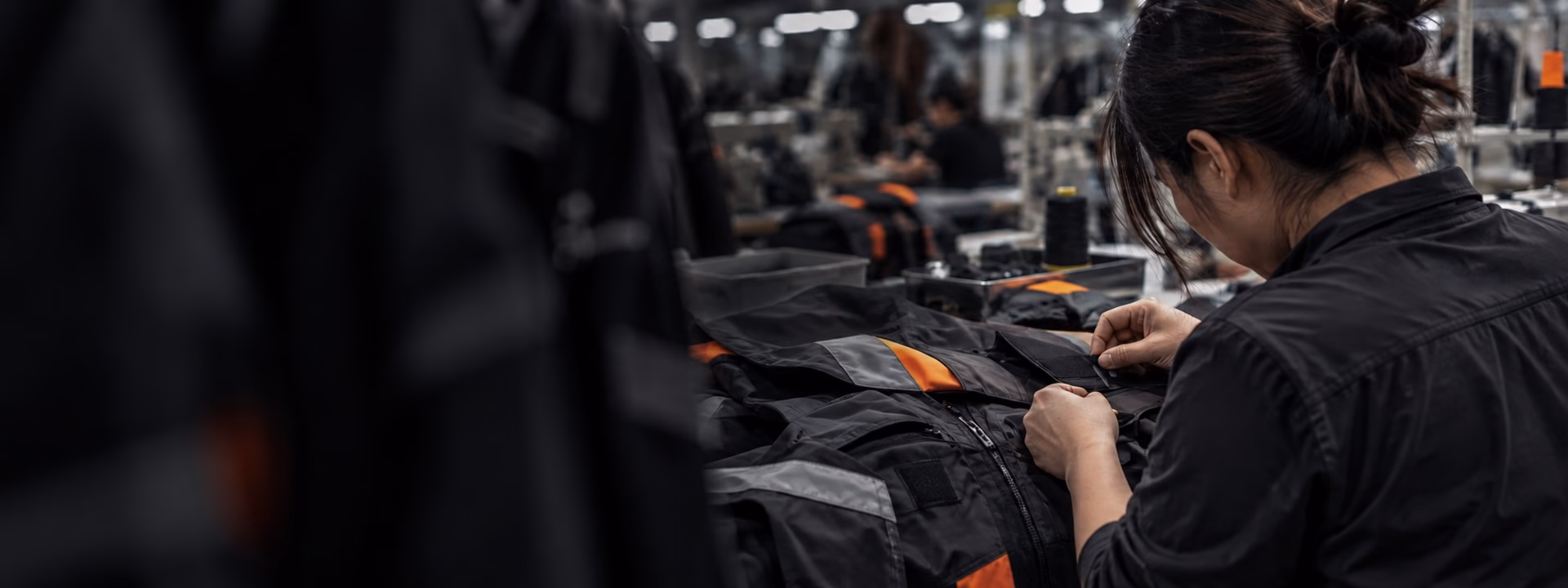 Worker handling technical construction details on a functional garment during manufacturing